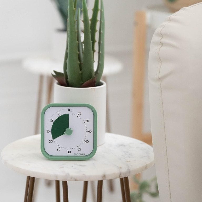 ADHD timer clock on side table with cactus plant in modern living room.