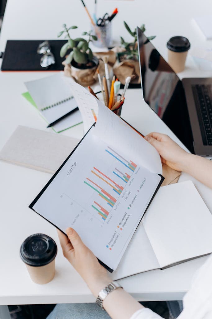 Hands reviewing graphs and charts in a modern office setting, analyzing data trends.