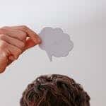 Person holds blank speech bubble above head, white background.