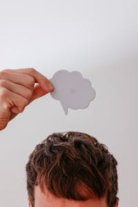 Person holds blank speech bubble above head, white background.