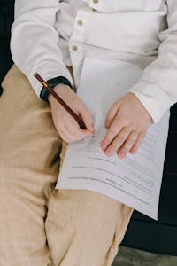 Young child writing on a sheet of paper, focusing on hands in a close-up view.