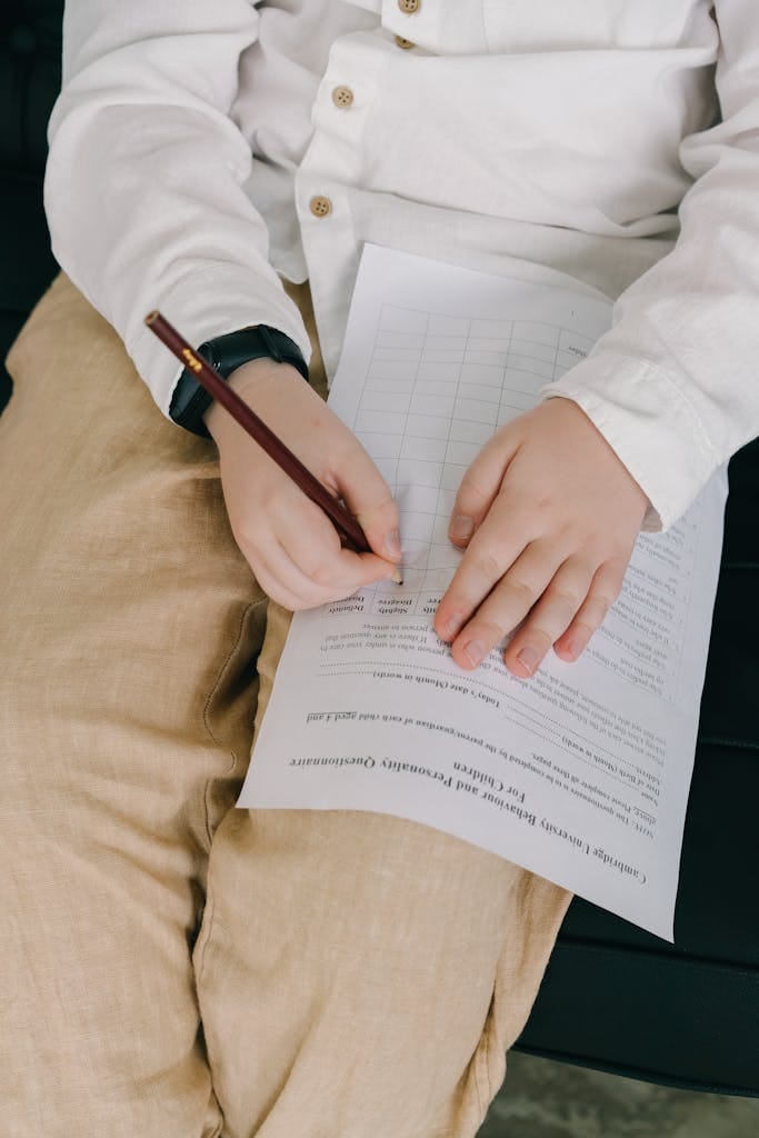Young child writing on a sheet of paper, focusing on hands in a close-up view.