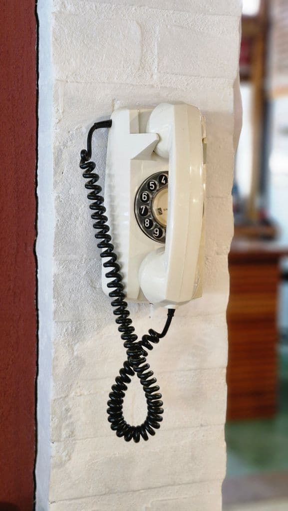 Classic rotary phone on a white brick wall, capturing a nostalgic retro vibe.